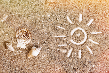 Simple sun drawing in the sand and seashellsの写真素材