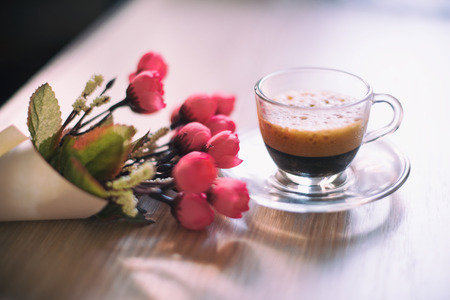 Wooden table with cup of coffee and flowerの写真素材