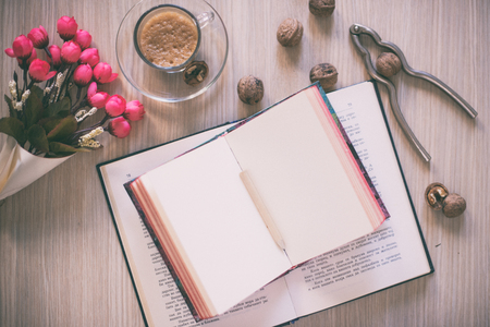Notebook, cup of coffee and flower on wooden tableの写真素材