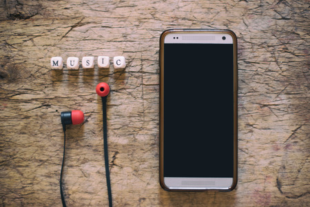 Music word on wooden cubes, with cell phone and earphonesの写真素材