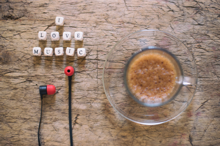Word I Love Music, cup of coffee and earphones on wooden tableの写真素材