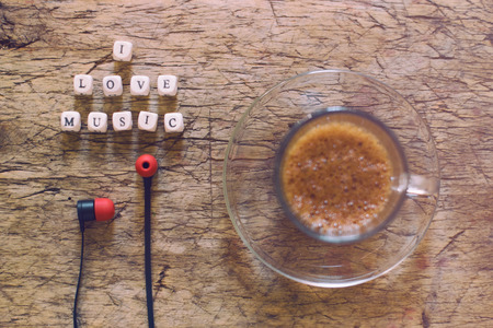 Word I Love Music, cup of coffee and earphones on wooden tableの写真素材