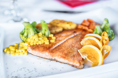Grilled salmon with spring vegetables on white plateの写真素材
