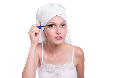 Woman applying black mascara on eyelashes with makeup brushの写真素材