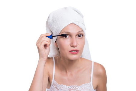 Woman applying black mascara on eyelashes with makeup brushの写真素材