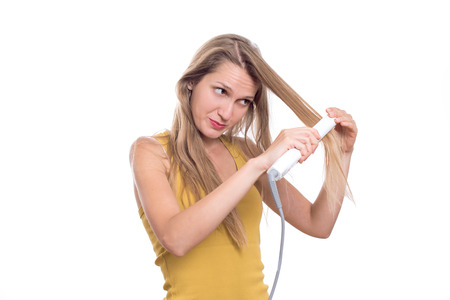 Young woman straightening her hair using hair straightenerの写真素材