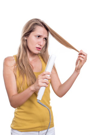 Young woman damage her hair with straightening ironの写真素材