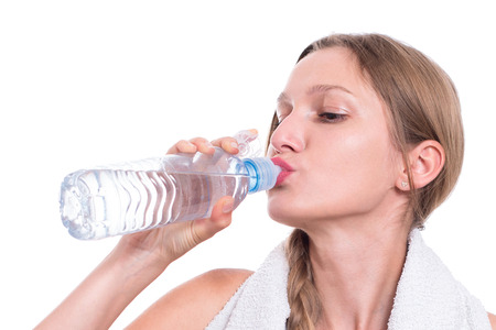 Sporty woman drinking water, isolated on white backgroundの写真素材