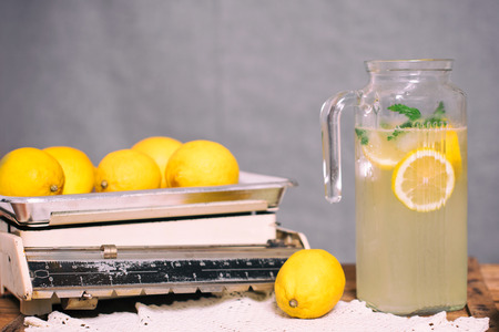 Preparation of the lemonade drink. Lemonade in the jug and lemons with mint on the tableの写真素材