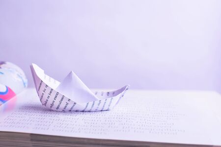 Paper boat sails on open bookの写真素材
