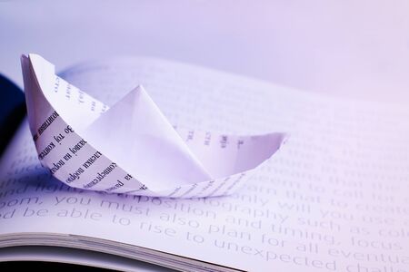 Paper boat sails on open bookの写真素材
