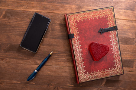 dark table with vintage book and pen next to a heartの写真素材
