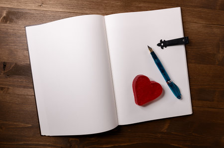 dark table with vintage book and pen next to a heartの写真素材