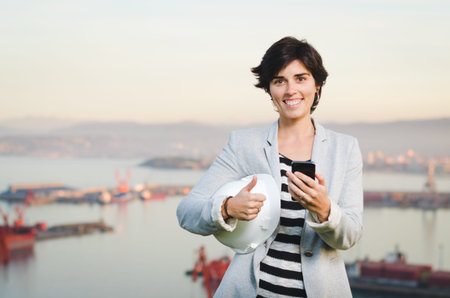 successful independent engineer woman smiling and looking to the camera, on industrial harbor with...