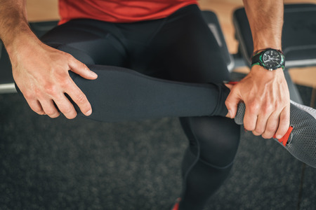 Fitness man stretching leg for warming up before gym indoor workout. Male athlete exercising before running or working out.の写真素材