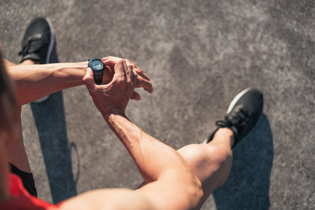 Fitness man resting during outdoor cross training workout reseting watch counter. Fit fitness sport...