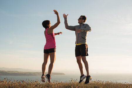 Fitness running couple giving five while jumping outdoor after running training workoutの写真素材