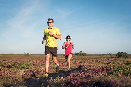 Sporty couple running outdoor cross country. Woman and man doing cardio
exercise workout.の写真素材