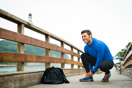 Fit runner sportsman holding ankle in pain in a park. Broken twisted joint running sport injury. Athletic man touching foot due to sprain.の写真素材