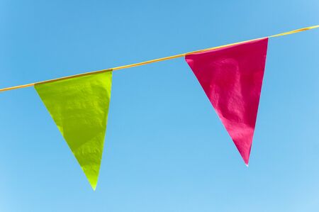 Garland of red and green triangular festive flags against blue skyの写真素材