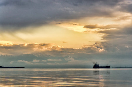 Dramatic sunset and floating ship on horizonの写真素材