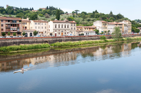 FLORENCE, ITALY - June 04, 2011 :Man riding canoe on Arno river with residential buildings on the shore, Florence, Italyのeditorial素材