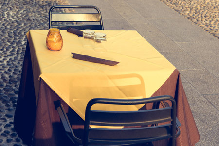 Toned image of table with yellow tablecloth and chairs on street cafe