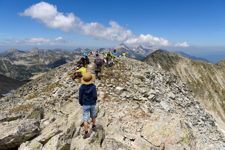 Pirin mountain, Bulgaria - June 25, 2017: Tourists on top of  Polezhan peak (2850,4 m) admire the view to Pirin national park in beautiful weatherのeditorial素材