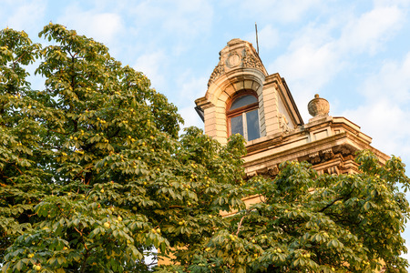 Ruse, Bulgaria - July 17, 2017: Chestnut tree tops and facade of renovated building with rich decoration behind themのeditorial素材