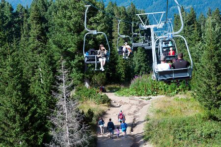 Rila mountains, Bulgaria - August 22, 2010: People riding chair lift up in the mountain and group of tourists walking underneathのeditorial素材