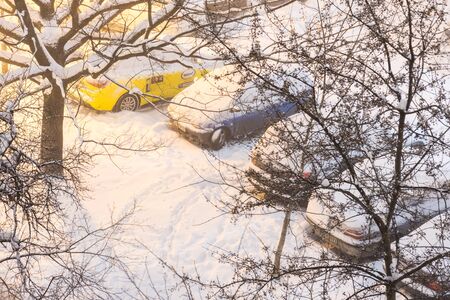 Sofia, Bulgaria - February 27, 2018: Aerial view through bare tree branches to snow covered cars on parking lot in the night with city lightsのeditorial素材