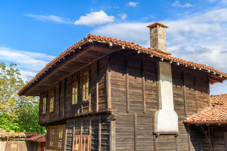 Old traditional rustic house made of wood with tile roof against blue sky, Zheravna, Bulgariaのeditorial素材