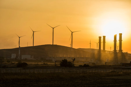 Silhouettes of two wind energy turbines in the sunset with red sky