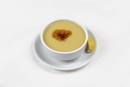 Lentil soup with parsley leaf sprig in a white porcelain bowl with plate and spoon isolated over white background.の写真素材