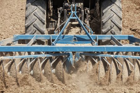 Tractor ploughing on the field in sunlightの写真素材