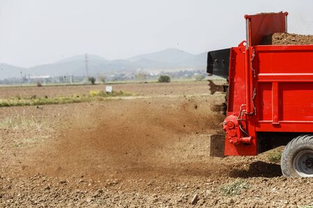 Agricultural scene of farmer manure spreading as agricultural background. Fertilising the field.の写真素材