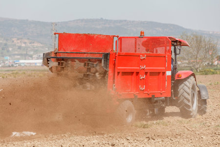 Agricultural scene of farmer manure spreading as agricultural background. Fertilising the field.