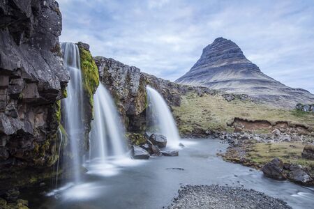 Kirkjufell is a free standing mountain of the Snaefellsnes peninsula, on the northern coast of Iceland. Together seen with the mountain, is a waterfall called Kirkjufellsfoss that flows into the sea.の写真素材