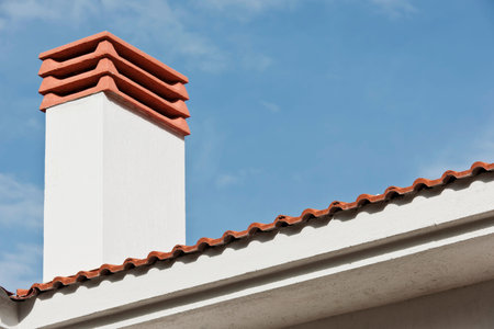 Red tile roof on the white house with blue sky and cloud background