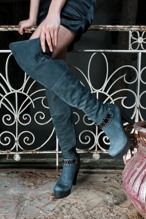Fashionable woman wearing black boots and high heels posing outdoors.の写真素材
