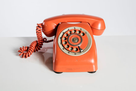 Old red telephone on a white background, closeup of photo.の写真素材