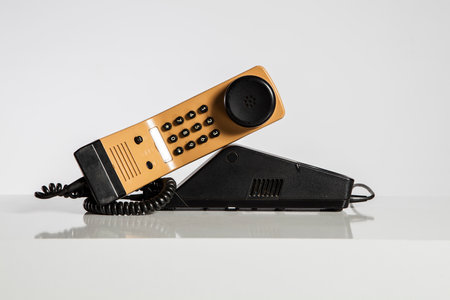 Old black and yellow phone on white background, closeup of photoの写真素材