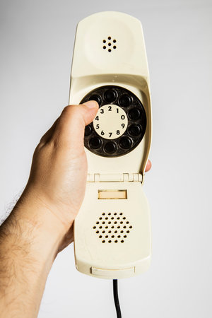 Closeup of a hand holding a telephone handset on a white backgroundの写真素材
