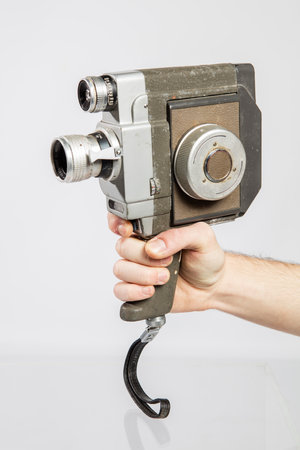 Old movie camera in hand isolated on white background. Studio shot.の写真素材
