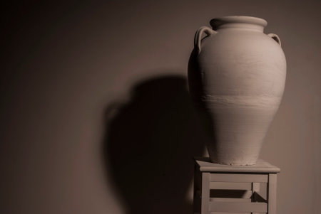 Clay vase on a white shelf with shadow on the wallの写真素材