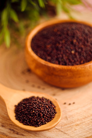 Black mustard seeds in a wooden spoon on a rustic background.の写真素材
