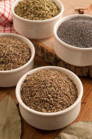 Poppy seeds, poppy seeds and cumin in bowls on wooden backgroundの写真素材