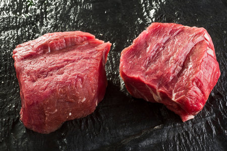 two pieces of raw beef meat on a black background, top viewの写真素材