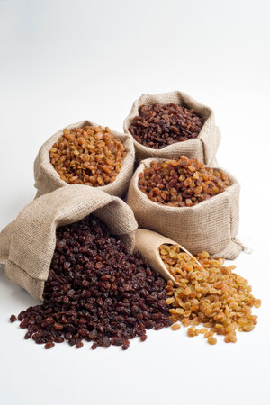 Dried raisins in bags and wooden spoon on white backgroundの写真素材