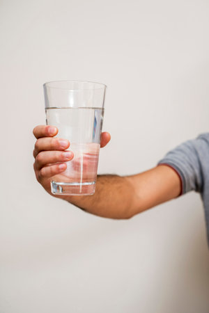 Close-up of man holding glass of water against white background with vignetteの写真素材